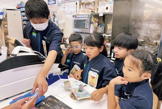 赤岩店長からレジ打ちを教わる子どもたち